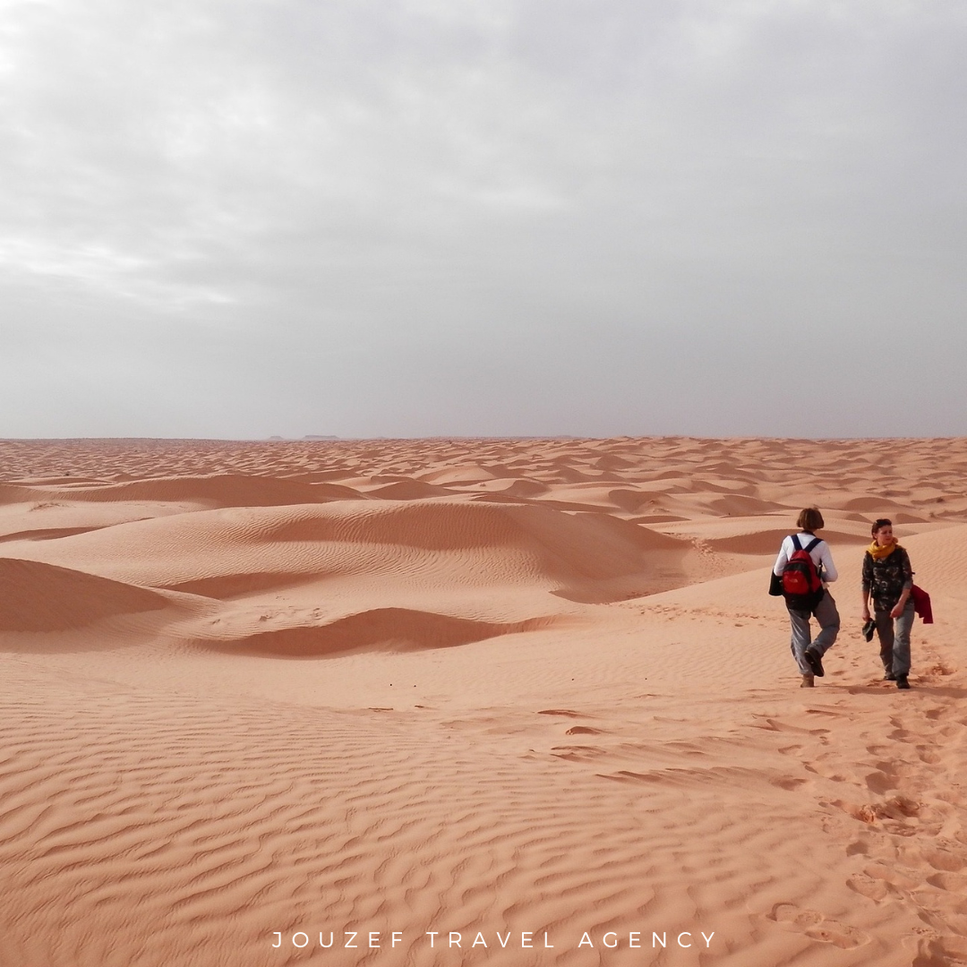 Two women taking a short walk on the dunes during a 4x4 desert tour in Douz