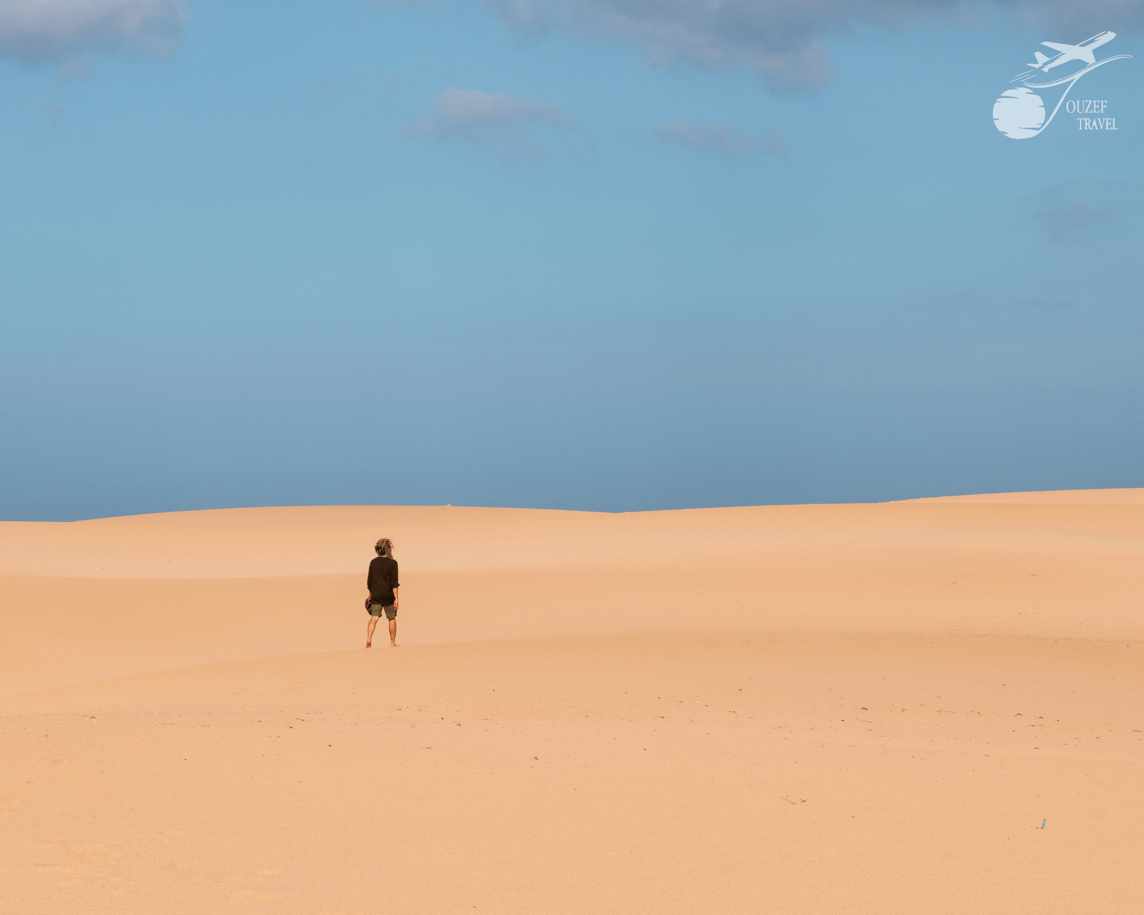 Person walking through the desert dunes of Ksar Ghilane oasis